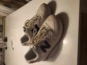 New Balance 574 i bra skick - New Balances i bra skick som är använda ca 10 gånger. Säljer dem pga att jag inte använder dem. Kvitto finns digitalt och de är ifrån zalando men det finns ingen kartong. Skorna är vit/beige färgadd.