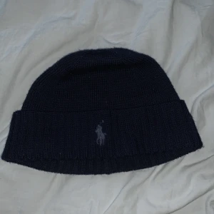 Ralph Lauren mössa  - Skön Ralph lauren mössa i tyg.  Skön på vintern då den håller värme bra. Använd ett par gånger. Mycke bra skick 
