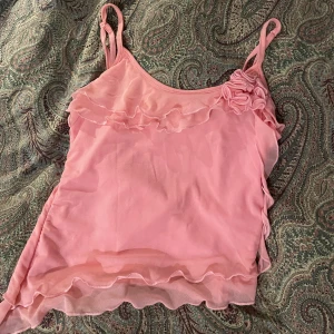 Gulligt linne  - Super söt topp men volanger. Bra material och en fin färg. Klädesplagget är knappt använt då den var för liten för mig🥹 