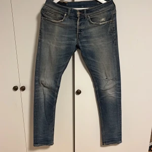 Dondup George Jeans stl 31  - Säljer nu dessa Dondup jeansen i Modellen Georg skinny fit. Dom är i använt skick och laggade två gånger där bak(se bild 2) Utöver det är det bara två små hål på knäna som enkelt går att laga. Jag är 188. Vid frågor är det bara och hör av sig. 