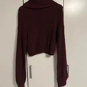 En jättefin stickad vinröd tröja med en löst sittande polokrage som är anings kortare än en vanlig tröja. Tröjan är använd men inget som märks
