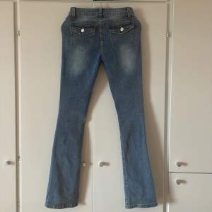 Jättesnygga low waist jeans med trendiga fickor där bak och en liten detalj vid framfickan, sitter jättefint och säljer pågrund av att dem inte kommer till användning. 