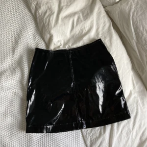 Minikjol, lateximitaion - En minikjol i lateximitation/läderimitation, den har inga skador. Ganska liten i storleken, jag har växt ur den:)