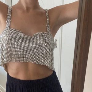Glittrig topp i metall - Supersnygg glittrig topp i metall med strass⚡️ Köpt second hand och inte kommit till användning, varav jag nu säljer den. Den passar xs-s och knäpps med en kedja i ryggen. OBS: på flera ställen har det försvunnit stenar, skriv för fler bilder på det!🪩