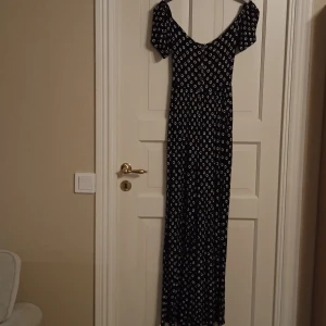 Jumpsuit med öppen rygg - Asos blommig avslappnad helkroppsdräkt med öppen rygg. Knappar framtill. Vida ben.