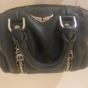 ÄKTA ZADIG VÄSKA 💼  - En svart Zadig väska i storlek xs och modellen Sunny ⭐️ Mycket använd! Den har förlorat lite färg i mitallen, men detta går att fixa ! Väskan går absolut att piffa till och tvätta!❤️