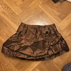 så söt snedskuren kjol i brunt/brons med många lager och fina detaljer