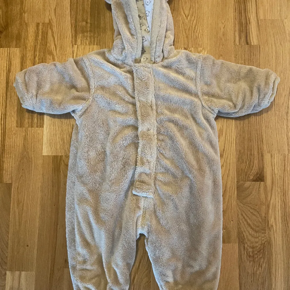 Teddy overall med öron Fint begagnat skick Märke: Cocoon  Ej vanlig storleksmärkning, bild 4 visar storlekslappen. Det står 71.  När jag lägger denna ovanpå en overall med storlek 68 så är denna något större så rimligtvis är denna något mellan 68-74.. Jackor.