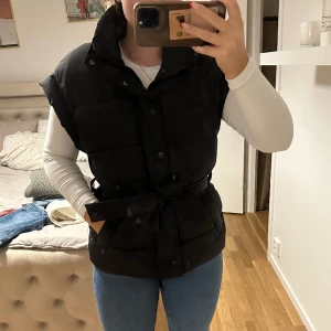 Tjockare väst - Svart lite tjockare väst med både dragkedja, knappar och snöre, stor i storleken