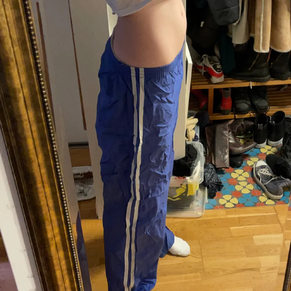 Blåa track pants med två vita ränder. Långa i benen och passar många storlekar då e är mycket stretchiga. Har också syr in dem lite i midjan men det går lätt att spreta up. . Jeans & Byxor.