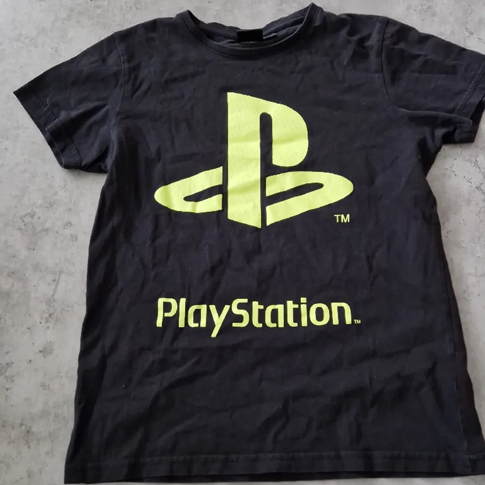 En svart PlayStation tischa, barnstorlek 146-152, 8 av 10.. T-shirts.