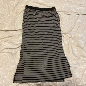 Här säljer jag en lång randig kjol som har aldrig används för att jag har inte vetat när jag ska ha den. Den är grå med svarta ränder och har två slittar på sidorna samt en liten stjärna på vänster sida. 