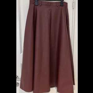 Skinn kjol - vinröd - Lång kjol i skinn material. Har färgen mörk vinröd. Den är endast använd 1 gång. Helt ny i skick. Priset kan diskuteras.