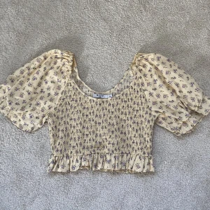 Gul blommig blus  - En jättefin gul blus med lila blommor som tyvärr inte kommer till användning. Den är köpt på NA-KD o är endast använd 1 gång. Säljs för 100kr & köparen står för frakten 💛sista bilden är lånad 