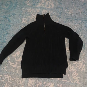 Tröja - Svart stickad tröja. Lite längre modell. Dragkedja så man kan ha kragen öppen eller stängd. Taggen säger xs men skulle snarare säga s eller m