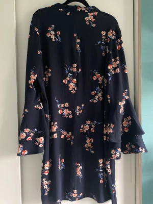 Superfin sommarklänning  - Snygg, kort klänning i storlek L från Indiska. Mörkblå med blommor och härliga ärmar. Använd en gång och nu är den tyvärr för liten för mig.