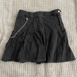 Jeanskjol med kedja - En grå jeanskjol med en kedja på sidan. Kedjan går även att ta bort om man vill det. Kjolen är använd max 3 gånger. Kontakta mig om du har fler frågor 🙂