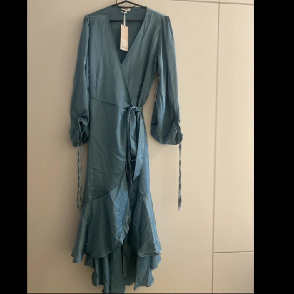 Gilda Wrap Dress BUBBLEROOM OCCASION. Helt ny klänning som inte har använts och kan inte lämna tillbaka. Köpt för 999kr. Storlek XL. Färgen är Petrol-green. . Klänningar.