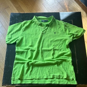 *brat* Grön pikétröja från Ralph Lauren - Säljer en snygg grön pikétröja från Ralph Lauren. Den har en klassisk krage med två knappar och det ikoniska broderade logotypen på bröstet. Perfekt för en avslappnad men stilren look. Passar bra till både jeans och shorts!