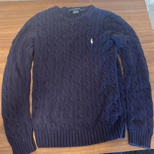 Ralph Lauren  - Säljer en skit snygg Ralph Lauren tröja. Färgen är mörk blå. Längden är 65 cm, längden vid armen är ungefär 60 cm och midjan är 40cm Väldigt bra,använt några få gånger med inga hål. Nypris runt 1500kr. Tar byten Hör av dig vid mer frågor eller bilder