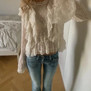 Vit blus med volanger - Säljer en superfin vit genomskinlig blus med volanger och prickigt mönster. Perfekt för en utekväll, fin middag med tjejerna eller fest!! Ger väldigt mycket struktur och intryck i en outfit, passar bra med ett par jeans/kostymbyxor.  Köpt secondhand på arkivet, använd fåtal ggr. Lik Ida Sjöstedt.
