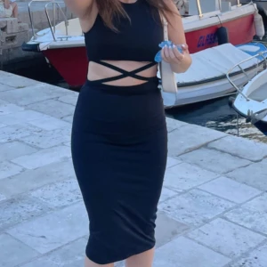 Svart knälång klänning med kryss framsida - En knälång svart klänning med detaljer framför, som ett kryss. Super snygg och skön till sommaren