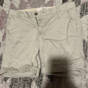 Beige shorts - Säljer ett par beige shorts i bomull. De har en normal passform med knappar och dragkedja framtill. Perfekta för sommaren!