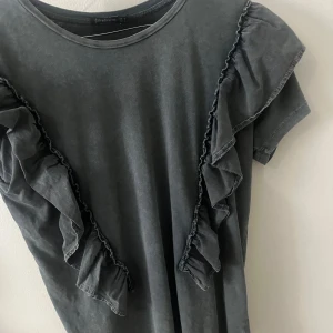 Detaljerad topp med volanger - Fin topp med fina volanger som är köpt för länge sedan! Väldigt fina volanger och har en snygg slitage-grå färg på sig som gör den ännu snyggare! 