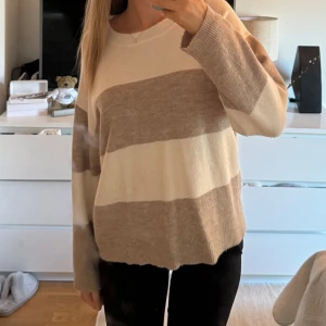 Randig stickad tröja  - En randig stickad tröja som är köpt i Danmark. Den är beige och vit. Jätte skön och snygg. Använd ett fåtal gånger. Säljer då den inte kommer till användning🥰