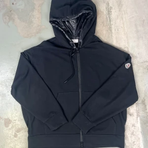Moncler - Born to Protect hoodie - Moncler luvtröja gjord av bomull. Maxi ton-i-ton bokstäver broderad på baksidan. Dragkedja framtill. Justerbar huva med dragsko. Två fickor framtill. Logopatch applicerad på ärmen. Invändig nylonhuva.   Storlek XL, storlek upplevs en aning mindre