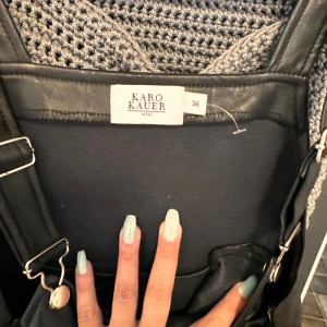 Svart skinnklänning från Karo Kauer - Säljer en supercool svart skinnklänning från Karo Kauer. Den har justerbara axelband och en tight passform som ger en snygg siluett. Perfekt för en utekväll eller fest! 🖤