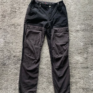 High mountain svarta/mörkgrå friluftsbyxor - Snygga svarta byxor med gråa detaljer. Byxorna har flera fickor och är i bra skick.
 
 Skick: Mycket bra
 Stl: Barn C170, är som en S/M
 Material: 34% bomull 63% polyester 3% Elastan
 Midjemått: 36cm x 2
 Innerbenslängd: 75cm
 Längd: 100cm