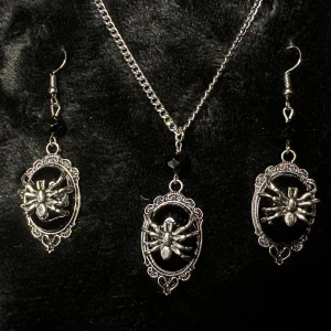 Smyckesset i vintagestil Halsband & örhängen m spindelmotiv Nytt Ovanligt Goth Rock Metal Punk Alternativ  - Nytt smyckesset i vintage/gothstil med matchande halsband och örhängen. medaljongerna i retrostil har silverfärgad utsirad infattning och svart bakgrund som framhäver de detaljerade spindlarna och svarta glittrande kristaller. Halsbandet har justerbar längd, max 55 cm samt hummerlås. Örhängena är 6,7 cm långa, 1,8 cm breda med krokar. Så ovanligt och blickfångande. Prutar inte men ger bundlerabatt. 