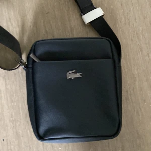 Lacoste väska - Mycket bra och inte använd. Pris kan sänkas vid snabb affär!