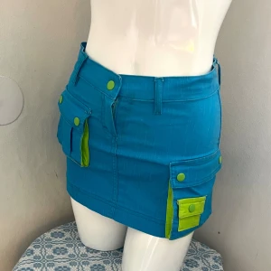 Minikjol turkos och limegrön!  - UNIK helt oanvänd cargo minikjol som inte går att få tag på nånstans. Jättefin blå och limegrön färg samt cargofickor så man ser ut som en cartoon-figur i den 🥹🙌34/Xs