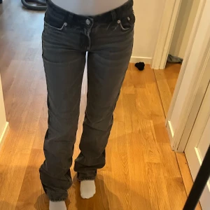 Grå jeans zara - Snygga grå jeansbyxor med en klassisk straight passform. Byxorna har en lågmidjad design och är utrustade med både knappar och dragkedja. Perfekta för en avslappnad stil.