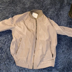 Beige bomberjacka från Dondup - Snygg beige bomberjacka från Dondup, tillverkad i Italien. Jackan har en dragkedja framtill och praktiska fickor med dragkedja. Perfekt för en stilren look. Jackan är i storlek 52 men den passar folk i storlek M/L skriv privat om frågor eller annat