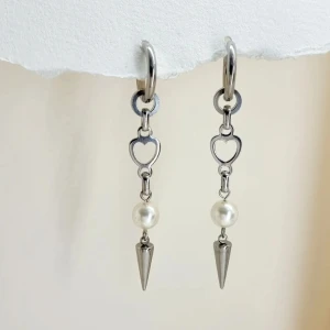 Silverörhängen med hjärta och pärla - Stilrena silverörhängen med hjärtformad detalj och hängande pärla. Handgjorda örhängen●Material- 100% rostfritt stål och pärlor ●Örhängeskrokar -rostfritt stål. Nickel fri. Längd -7cm.Vattentåliga, ändrar inte färgen! 
