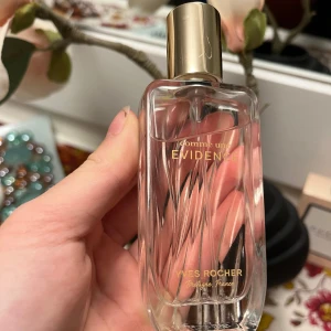 Comme Une Evidence Yves Rocher parfym - Elegant parfymflaska från Yves Rocher'Comme une Evidence' . Flaskan är genomskinlig med en subtil rosa ton och har en stilren design med ett gyllene lock. Perfekt för den som söker en sofistikerad och tidlös doft. En tidlös, elegant,lite fräscht, söt blomma, träig ros doft för kvinnor som älskar klassiker. Passar bra till vardagen men även om man ska ut. ALDRIG ANVÄND! ORGINAL PRIS ÄR RUNT 500-700kr. Tror den är 50ml flaska.🌸🪵🍄‍🟫
