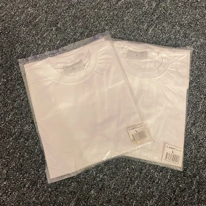 Vit t-shirt i bomull - Säljer två vita t-shirts i bomull, storlek L. Perfekta för en enkel och stilren look. T-shirtsen är kortärmade och kommer i förpackning.