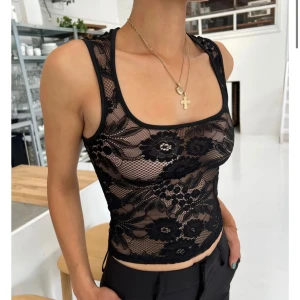 Venderbys spetslinne - Snyggt svart spetslinne med blommigt mönster. Linnet är ärmlöst och har en tight passform, perfekt för en stilren look. Detaljerna i spets ger en elegant touch. Den är vadderad så man behöver inte bh under 🥰