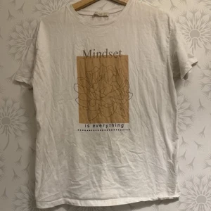 Vit t-shirt med tryck - Säljer en vit t-shirt med texten 'Mindset is everything' och ett stilrent tryck i beige. Perfekt för en avslappnad look.