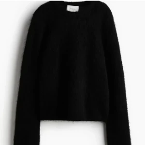Svart stickad tröja från hm - Snygg och stilren svart stickad tröja från H&M. Perfekt för kyliga dagar med sin mjuka och bekväma passform. Tröjan har långa ärmar och en klassisk rund halsringning.