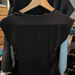 Svart topp med öppen rygg - Elegant svart topp med en stilren design och öppen rygg. Perfekt för en kväll ute eller en speciell tillställning.