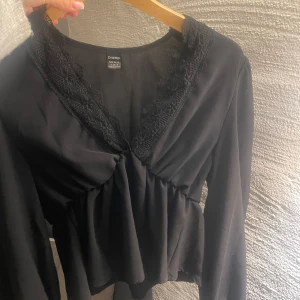 Svart blus  - Snygg svart blus med spetsdetaljer vid v-ringningen. Blusen har långa ärmar och en lätt rynkad midja som ger en fin passform. Perfekt för både vardag och fest! ( den är inte från bok bok vet ej vrf det står de) 