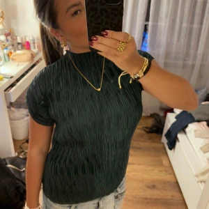 Mörkgrön ribbad topp - Säljer denna ribbade topp som är en superfin festtopp. Använd en gång så är i bra skick. Den är i en jättefin mörkgrön färg och kragen går upp lite upp på halsen. Färgen kommer inte riktigt fram i bilderna, skriv för fler bilder så kan jag försöka få bilder där den fina färgen kommer fram bättre!❤️