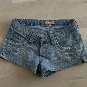 Blå jeansshorts från CND - Snygga blå jeansshorts från CND med låg midja och klassisk femficksdesign. Perfekta för sommardagar och avslappnade stunder. De har en bekväm passform och är gjorda i slitstarkt denim. Vintage 