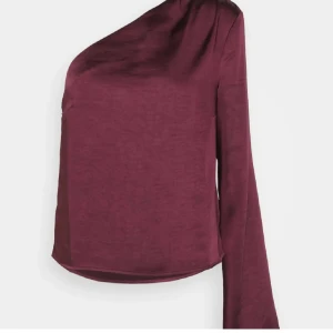 Vinröd oneshoulder topp - Snygg vinröd oneshoulder topp i satin med en lång ärm. Använd två gånger men har lite defekt (kom privat för bild)🥰 superfin till middag eller fest! Hör av dig om du har frågor eller funderingar🤗