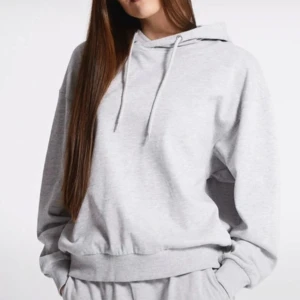 Grå hoodie - Säljer en bekväm och stilren grå hoodie med luva och dragsko. Perfekt för en avslappnad look. Den har en loose passform och långa ärmar.
