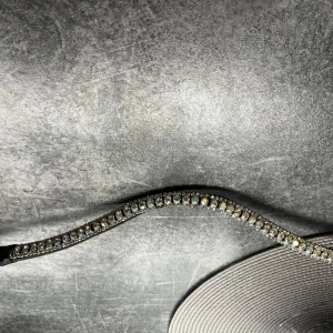 Glittrigt pannband  med strass  - Snyggt och glittrigt pannband till häst  med flera rader av strass som fångar ljuset vackert. Perfekt för att ge en extra touch av glamour . Svart skinn 